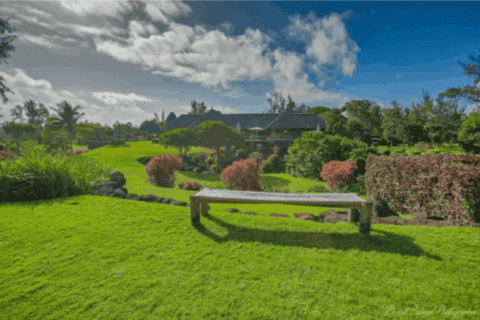 Gartenanlage der Bubble Lodge Ile aux Cerfs mit Sitzbank, Rasen und tropischer Vegetation