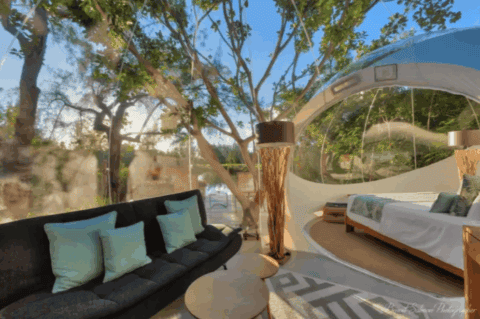 Wohnbereich der Bubble Lodge Ile aux Cerfs mit Sofa, rundem Tisch und Blick zum Schlafbereich