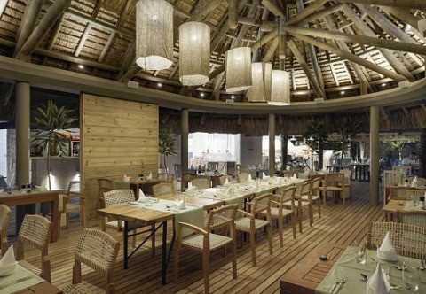 Restaurant im Coin de Mire Attitude mit Strohdach, Holzmöbeln und gedeckten Tischen