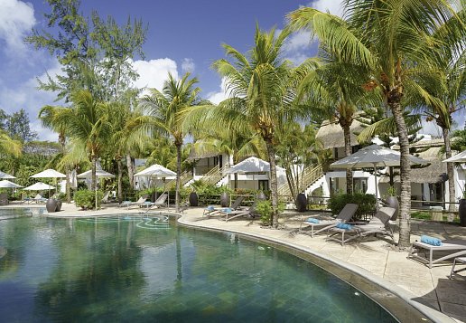 Poolbereich im Coin de Mire Attitude mit Sonnenliegen, Palmen und Hotelgebäuden