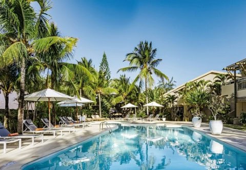 Poolbereich im Friday Attitude mit Sonnenliegen, Palmen und tropischem Garten