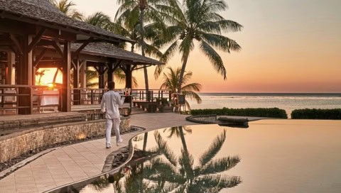 Poolanlage des LUX Le Morne bei Sonnenuntergang mit Palmen und Meerblick