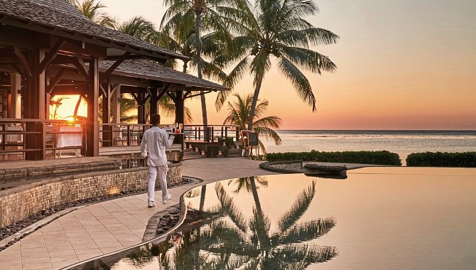 Poolanlage des LUX Le Morne bei Sonnenuntergang mit Palmen und Meerblick