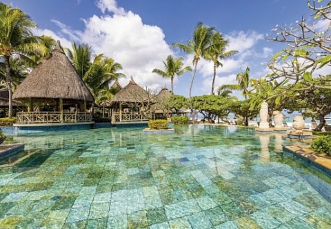 Türkiswasser-Pool umgeben von Palmen und traditionellen Strohdach-Bungalows