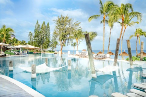 Poolbereich des Le Meridien Ile Maurice mit Wasserliegen, Palmen und Meerblick