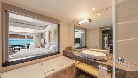 Badezimmer im Shangri-La Le Touessrok mit Badewanne, Waschtisch und Blick ins Schlafzimmer