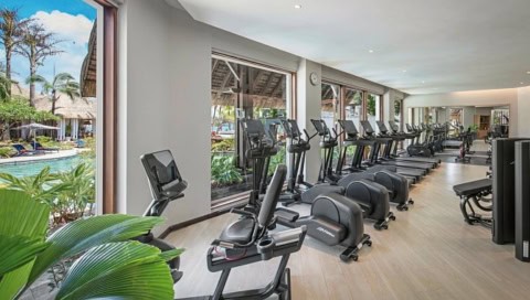 Moderner Fitnessraum im Shangri-La Le Touessrok mit Trainingsgeräten und Poolblick