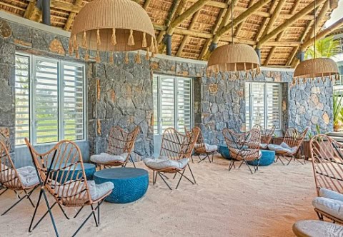 Lounge im Sunrise Attitude Belle Mare mit Steinwänden, Rattansesseln und Strohdach